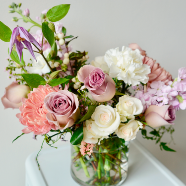 A delicate flower arrangement in soft pink, mauve, and white hues, featuring roses, carnations, and clematis. This romantic bouquet is perfect for anniversaries, birthdays, or to express your affection. Available for local delivery in Wake Forest, NC.