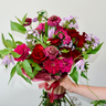 A vibrant, hand-tied bouquet featuring deep red roses, burgundy dahlias, and purple accents like clematis and phlox. This rich and textured bouquet is perfect for anniversaries, birthdays, or expressing sympathy. Available for local delivery in Wake Forest, NC.