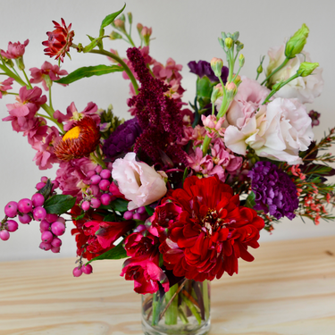 A vibrant and textured bouquet with deep red zinnias and dahlias, accented with pink, purple, and burgundy blooms. This eye-catching arrangement is perfect for anniversaries, birthdays, or making a bold statement. Available for local delivery in Wake Forest, NC."